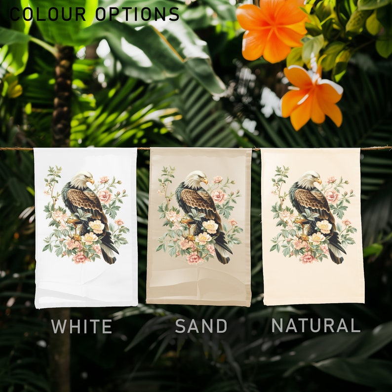 May include: Three garden flags with a brown eagle perched on a branch with pink flowers. The flags are displayed on a white, sand, and natural background. The text "COLOUR OPTIONS" is at the top of the image. The flags are labeled "WHITE", "SAND", and "NATURAL".