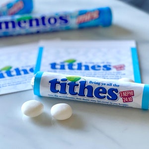 May include: A blue and white package of mints with the word "tithes" printed on it. The package is next to two white mints and a small white card with the word "tithes" printed on it. The card also includes a scripture reference: "Bring ye all the tithes into the storehouse, that there may be meat in my house." 3 Nephi 24:10