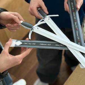 Könnte beinhalten: Ein Satz silberfarbener Schwerter mit schwarzen Griffen und Scheiden. Die Klingen tragen den Text "QUICK AND POWERFUL". Die Scheiden tragen die Texte "D&C 62:33", "Hebräer 4:12", "Alma 3:15" und "Epheser 6:17".