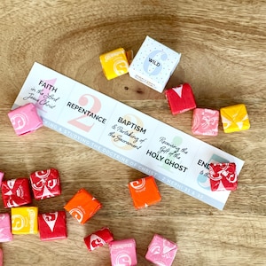 Könnte beinhalten: Eine weiße Karte mit den Worten "Glaube an den Herrn Jesus Christus", "Reue", "Taufe und Teilnahme am Abendmahl", "Empfang des Heiligen Geistes" und "Bis zum Ende ausharren" darauf gedruckt. Die Karte ist von bunten Süßigkeiten umgeben.