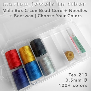 May include: A clear plastic storage box containing six spools of C-Lon bead cord in red, yellow, black, blue, dark blue, and silver, along with two needles and a piece of beeswax. Text reads: marion jewels in fiber, Mala Box C-Lon Bead Cord + Needles + Beeswax | Choose Your Colors, Tex 210, 0.5mm Ø, 100+ colors.