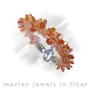 May include: A delicate bracelet made with iridescent orange and pink beads, arranged in a flower-like pattern. The bracelet has a silver clasp.