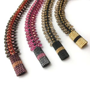 May include: Four beaded necklaces with different colour combinations. The necklaces are made with small, round beads in shades of brown, pink, and grey. Each necklace has a black and gold beaded end cap.