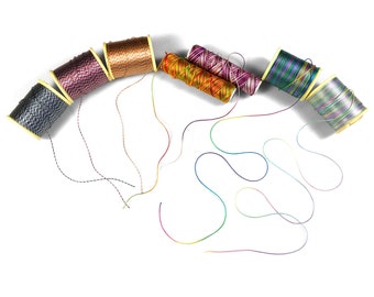 May include: A collection of colorful spools of thread with their ends unraveled and spread out on a white surface. The spools are arranged in a semi-circle shape, with the ends of the thread forming a pattern of loops and swirls.