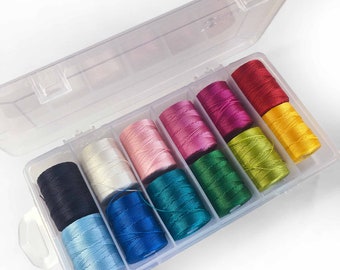 May include: A clear plastic storage box with 10 spools of colorful thread. The spools are arranged in a rainbow pattern, starting with black and ending with yellow.
