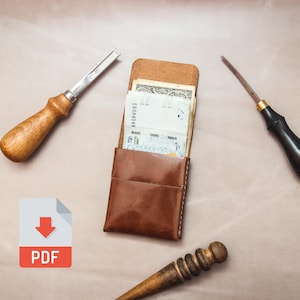 Op de afbeelding: Een bruine leren portemonnee met geld erin, omringd door leerbewerkingsgereedschap. De gereedschappen omvatten een beitel met houten handvat, een priem met zwarte handvat en een polijstmachine met houten handvat. Een PDF-pictogram staat linksonder.