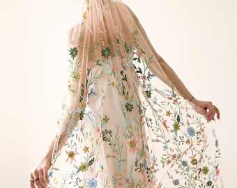 May include: A blush pink tulle bridal veil with floral embroidery in shades of green, blue, pink, and yellow.