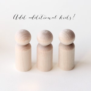 Puede incluir: Tres mu&ntilde;ecos de madera sin terminar con cabezas redondeadas. Los mu&ntilde;ecos est&aacute;n de pie sobre un fondo blanco. El texto "Add additional kids!" est&aacute; escrito en cursiva encima de los mu&ntilde;ecos.