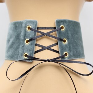May include: A gray velvet choker with black ribbon lacing and gold eyelets.