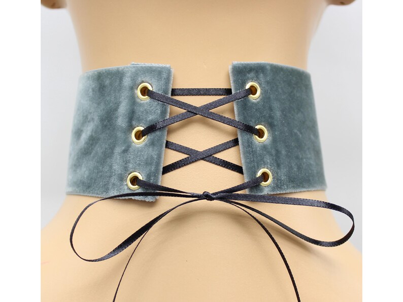 May include: A gray velvet choker with black ribbon lacing and gold eyelets.