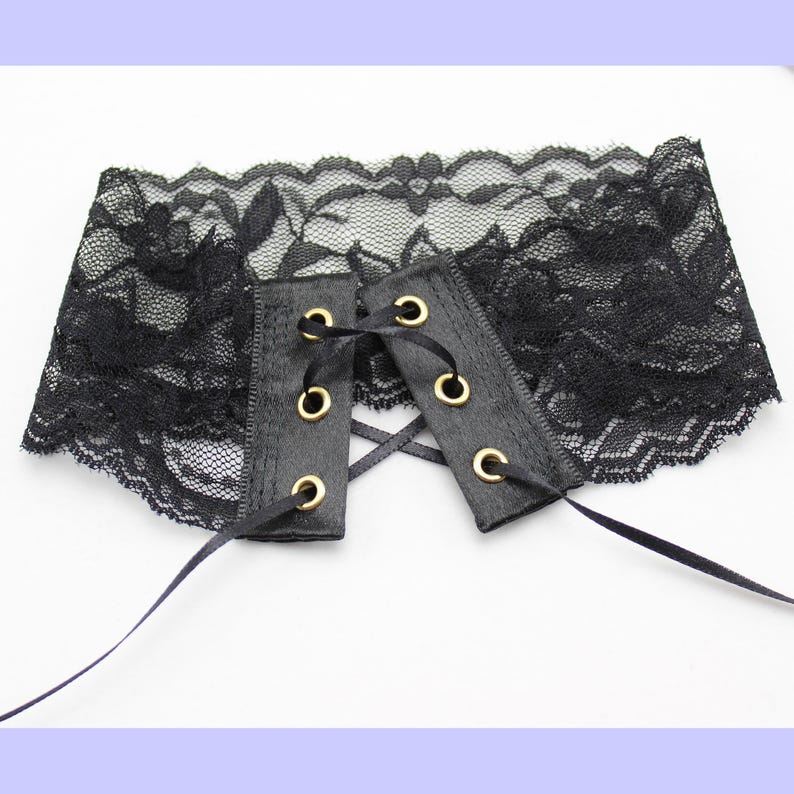 May include: Black lace choker with a satin ribbon tie and gold eyelets.