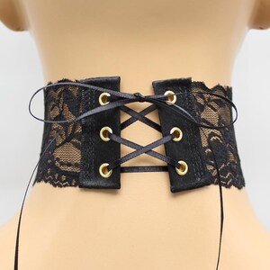 May include: Black lace choker with a satin ribbon tie and gold eyelets. The choker is adjustable and can be tied at the back of the neck.