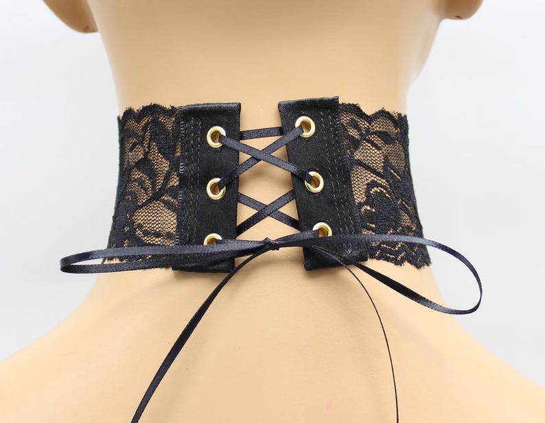 May include: Black lace choker with a satin ribbon tie and gold eyelets. The choker is adjustable and can be worn as a statement piece or a subtle accessory.
