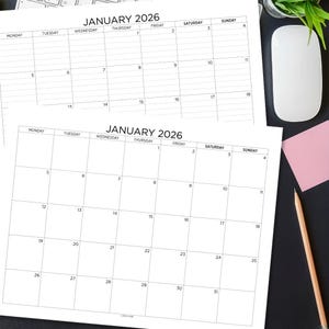 以下が含まれることがあります： 2026年1月の2つの白い紙カレンダー。各月の日のグリッドレイアウトです。カレンダーは暗い表面にあり、コンピューターマウス、鉛筆、ピンクの付箋が背景にあります。