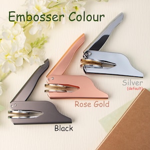 May include: Three embosser stamps in different colors: silver, rose gold, and black. The stamps are made of metal and have a round design. The text "Embosser Colour" is at the top of the image. The text "Silver (default)" is below the silver stamp, "Rose Gold" is below the rose gold stamp, and "Black" is below the black stamp.