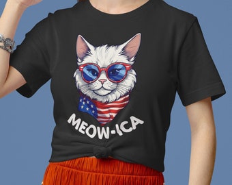 May include: Black t-shirt with a white cat wearing sunglasses and a bandana with the American flag design. The text "MEOW-ICA" is printed below the cat.