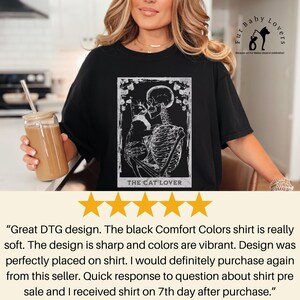Puede incluir: Camiseta negra con un dise&ntilde;o blanco de un esqueleto abrazando a un gato, con el texto "THE CAT LOVER". Pertenece a la colecci&oacute;n "Fur Baby Lovers".