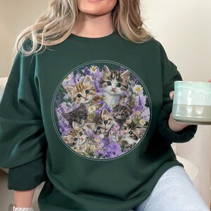 Gildan 18000 sweatshirt with vintage-style illustration of six playful kittens among lavender and wildflowers; cozy cottagecore cat lover crewneck for nostalgic and whimsical fashion.