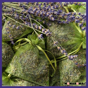 May include: A group of green mesh bags filled with dried lavender flowers. The bags are tied with green ribbon and are arranged in a pile. The lavender flowers are a light purple color and have a delicate fragrance.