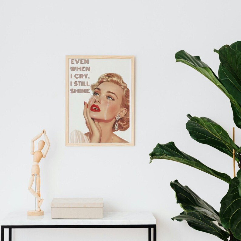May include: A vintage-style poster featuring a woman with blonde hair and red lipstick crying. The text on the poster reads "Even when I cry, I still shine."