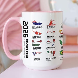 Peut inclure: Mug en c&eacute;ramique blanche avec une anse et un bord roses. Il pr&eacute;sente un calendrier du Grand Prix de Formule 1 2026 avec les trac&eacute;s et les dates des courses, dont Melbourne, Shanghai et Austin. Le mug mesure environ 10 cm de haut.
