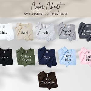 May include: A colour chart showing sweatshirt colours. The chart includes White, Sand, Ash, Sport Grey, Dark Heather, Black, Military Green, Navy, Light Blue, Light Pink, and Dark Chocolate. The text "Colour Chart" and "SWEATSHIRT - GILDAN 18000" are at the top.