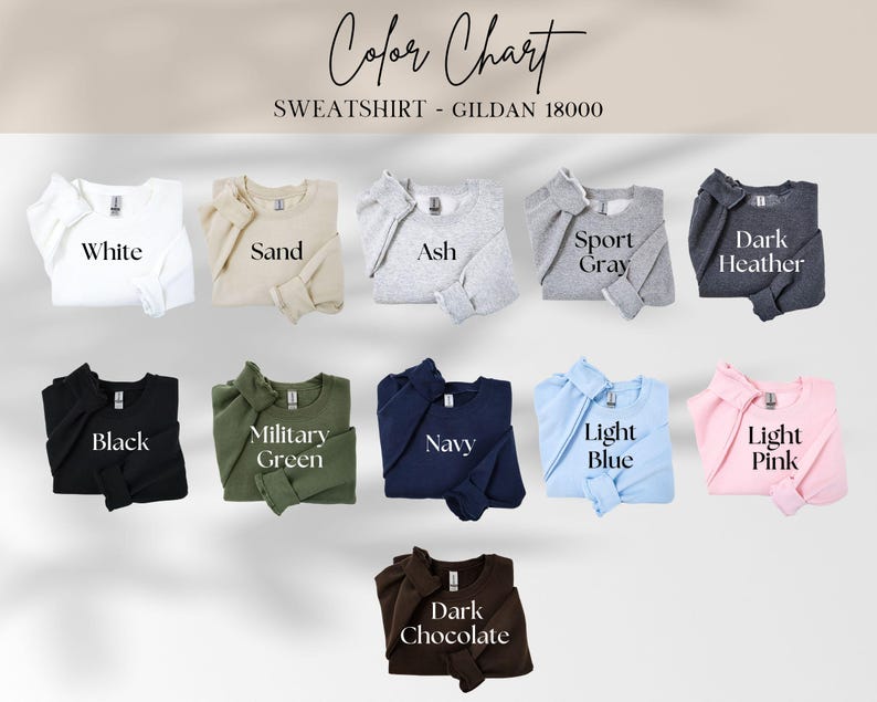 May include: A colour chart showing sweatshirt colours. The chart includes White, Sand, Ash, Sport Grey, Dark Heather, Black, Military Green, Navy, Light Blue, Light Pink, and Dark Chocolate. The text "Colour Chart" and "SWEATSHIRT - GILDAN 18000" are at the top.