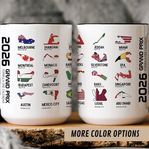 Peut inclure: Deux mugs en c&eacute;ramique blancs avec des anses et des bords noirs. Chaque mug pr&eacute;sente un calendrier de Formule 1 2026 avec les lieux et les dates des courses. Les mugs ont le texte "2026 GRAND PRIX FORMULA ONE CALENDAR" et "MORE COLOR OPTIONS".