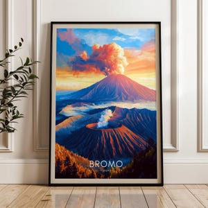 May include: A framed wall art print depicting a volcanic landscape with a large mountain emitting a plume of smoke under a vibrant sunset sky. The foreground features a smaller crater with white steam, and the text BROMO JAVA is printed at the bottom.