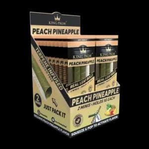 Pode incluir: Uma caixa expositora de mini rolos King Palm Peach Pineapple. A caixa é bege e preta com o texto Peach Pineapple, Terpene Infused e 2 Minis Holds 1g Each. A embalagem apresenta ilustrações dos rolos de folha verdes.