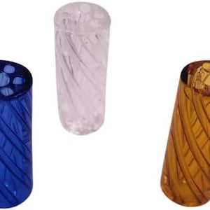 May include: Three decorative toothbrush holders in blue, clear, and amber. Each holder is cylindrical with a spiral design and a top with multiple holes. The holders are made of a transparent material.