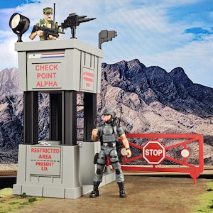 May include: A gray toy checkpoint with the text "CHECK POINT ALPHA" and "RESTRICTED AREA PRESENT I.D." A toy soldier stands in front of a red gate with a stop sign. Another toy soldier is on top of the checkpoint.