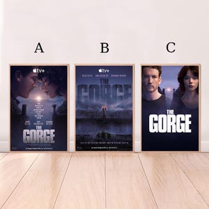 Puede incluir: Se muestran tres carteles enmarcados de la película "The Gorge". Cada cartel presenta los rostros de los actores y el título en letras blancas grandes. Los carteles tienen una combinación de colores oscuros, con el logotipo de Apple TV+ en la esquina superior izquierda.