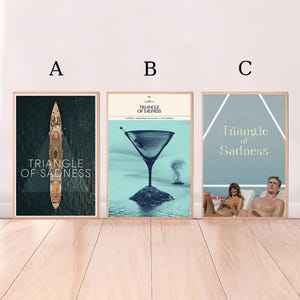 Puede incluir: Tres carteles enmarcados con el título "Triangle of Sadness". El primer cartel muestra un barco sobre agua oscura. El segundo cartel presenta una copa de martini. El tercer cartel muestra a dos personas en una playa.