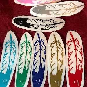 May include: Assortment of colorful feather decals in various colors, including pink, gray, black, teal, green, blue, gold, and red. The decals are on a white background.
