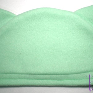 Pu&ograve; includere: Un cappello in pile verde menta con due orecchie a punta. Il cappello ha una corona arrotondata e un bordo ripiegato. Il cappello &egrave; di colore pieno ed &egrave; realizzato in un materiale morbido e soffice. Il cappello &egrave; progettato per assomigliare a un gatto.