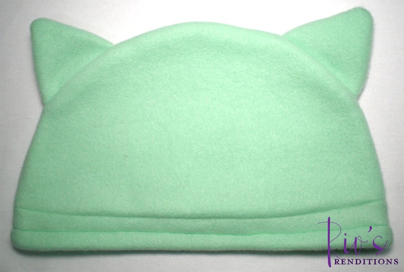 Pu&ograve; includere: Un cappello in pile verde menta con due orecchie a punta. Il cappello ha una corona arrotondata e un bordo ripiegato. Il cappello &egrave; di colore pieno ed &egrave; realizzato in un materiale morbido e soffice. Il cappello &egrave; progettato per assomigliare a un gatto.