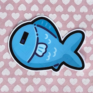 May include: A blue fish sticker with a black outline. The fish has a white belly, a small fin, and three small curved lines. The sticker is on a pink background with white heart shapes.