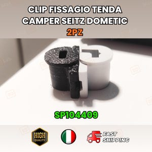 May include: A black and white plastic clip for a camper awning. The clip has a square hole and a unique shape. The text "CLIP FISSAGIO TENDA CAMPER SEITZ DOMETIC 2PZ" is at the top. The text "SP104409" is in green.