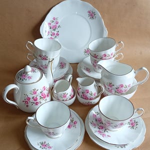 Peut inclure: Un service à thé vintage avec un motif floral. L'ensemble comprend une théière, un pot à crème, un sucrier et six tasses à thé et soucoupes. Les tasses à thé et les soucoupes ont une délicate bordure dorée.