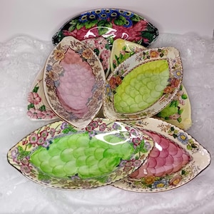 Colecciones de platos ovalados de cerámica Maling Pottery Lustreware en tonos rosa y verde, ideales para servir postres, como cuencos decorativos y funcionales.