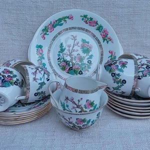 May include: A vintage tea set featuring floral patterned cups and saucers. The set is white with a delicate floral design in shades of pink, green, and blue. It includes a teapot, a creamer, and a sugar bowl.