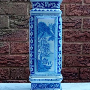 May include: A blue and white porcelain vase featuring a traditional Chinese landscape design. The vase has a square body and a wide base with intricate details.