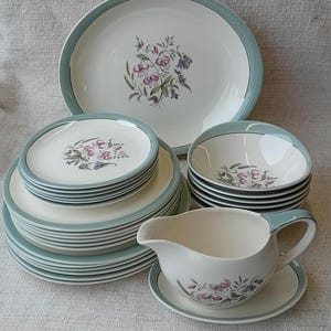 May include: A vintage floral patterned dinner service in shades of green, white and pink. The set includes plates, bowls and a gravy boat.