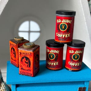 May include: Four vintage coffee canisters, two red with black lids and the text "Old Judge Vacuum Packed Coffee", and two orange with gold lids and the text "Hercules Pure Coffee".