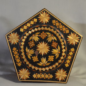 May include: A pentagonal wooden box with a geometric pattern of stars and diamonds in shades of brown, orange, and black.