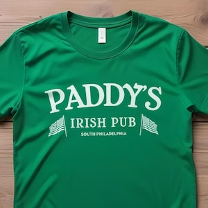 May include: Green t-shirt with white text that reads "Paddy's Irish Pub South Philadelphia" with two small American flags on either side of the text.