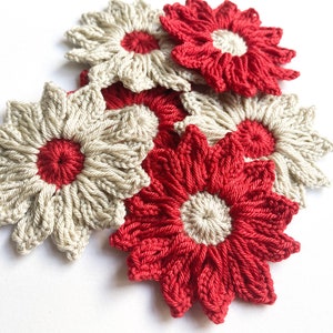 Puede incluir: Un grupo de flores de ganchillo en rojo y beige. Las flores tienen un diseño sencillo con un círculo central y varios pétalos.