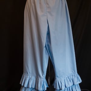 May include: Light blue cotton bloomers with multiple layers of ruffles at the bottom. The bloomers have an elastic waistband.