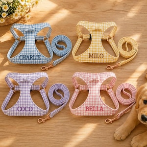Puede incluir: Cuatro arneses para mascotas con correas a juego en patrones de cuadros vichy azul, amarillo, morado y rosa. Cada arnés tiene un pequeño lazo en la parte superior y está bordado con los nombres Charlie, Milo, Coco o Bella en hilo.